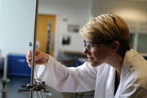 Adult learner in lab coat performing an experiment in a science lab.