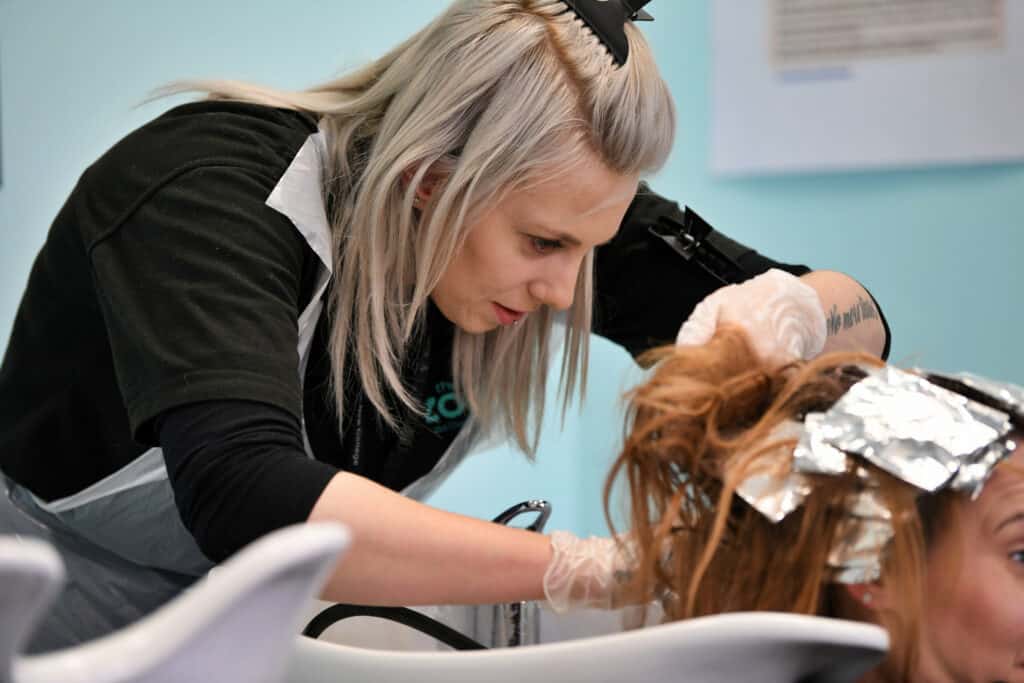 A female adult learner in a hairdressing salon with a client.
