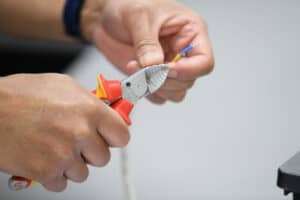 Close up of learner cutting wire with wire cutters