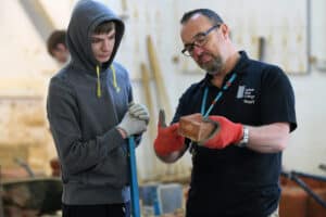 Brickwork lecturer demonstrating skill to male learner.