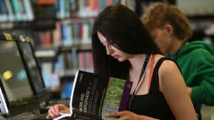 Female learner reading a book in the College library