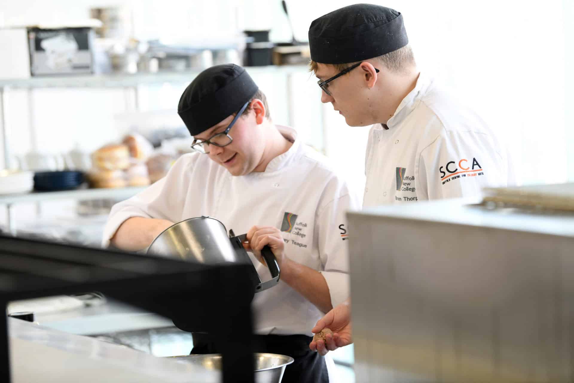 Two male catering learners working in a commercial kitchen