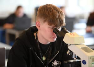 Male science learner using a microscope in a science lab.
