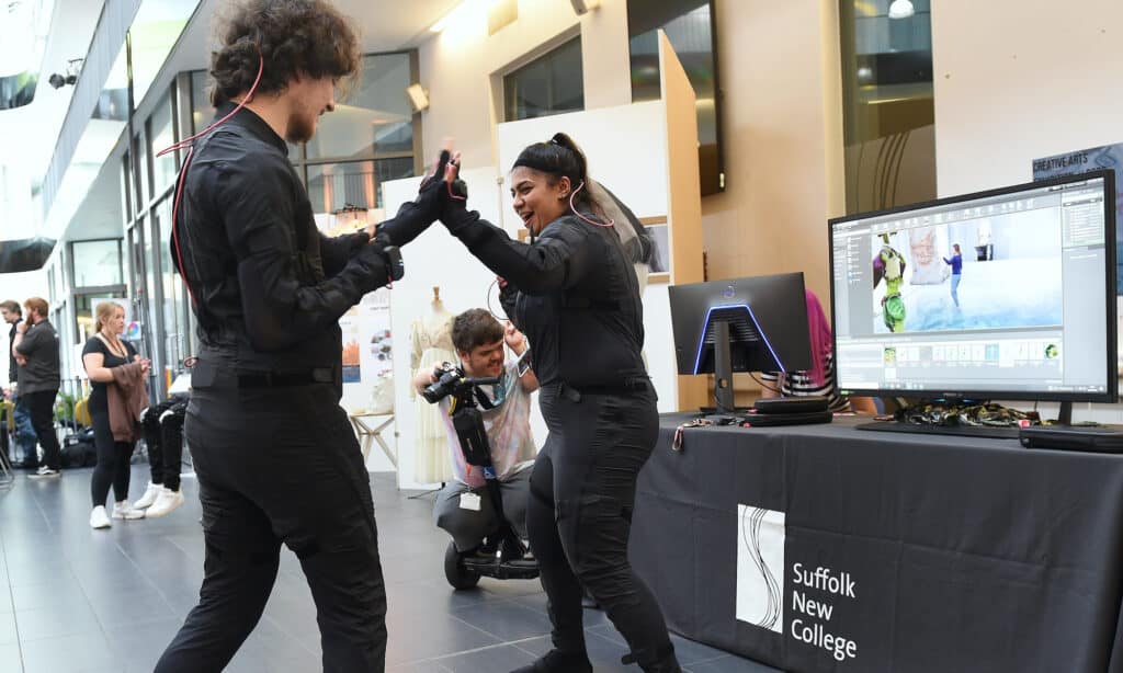 College learners in motion capture suits giving each other a high give during a showcase event with school leavers