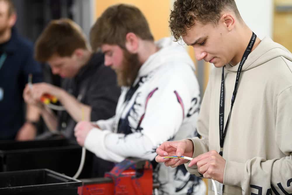 Learners stripping wire in electrical workshop