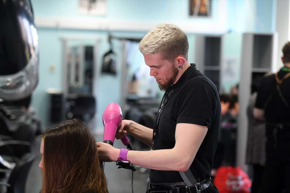 A hairdressing learner blowdrying a clients hair