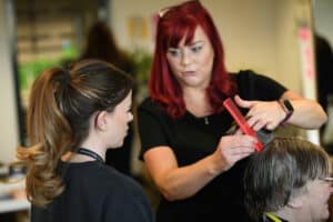 Hairdressing learner watching demonstration.