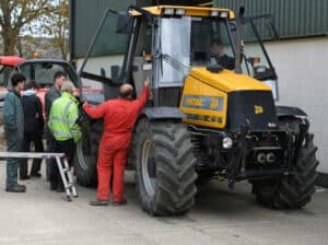 Learners working on a Yellow JCB tractor