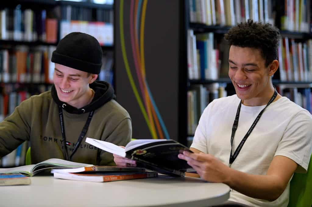 Two learners sitting in the learning curve reading books.
