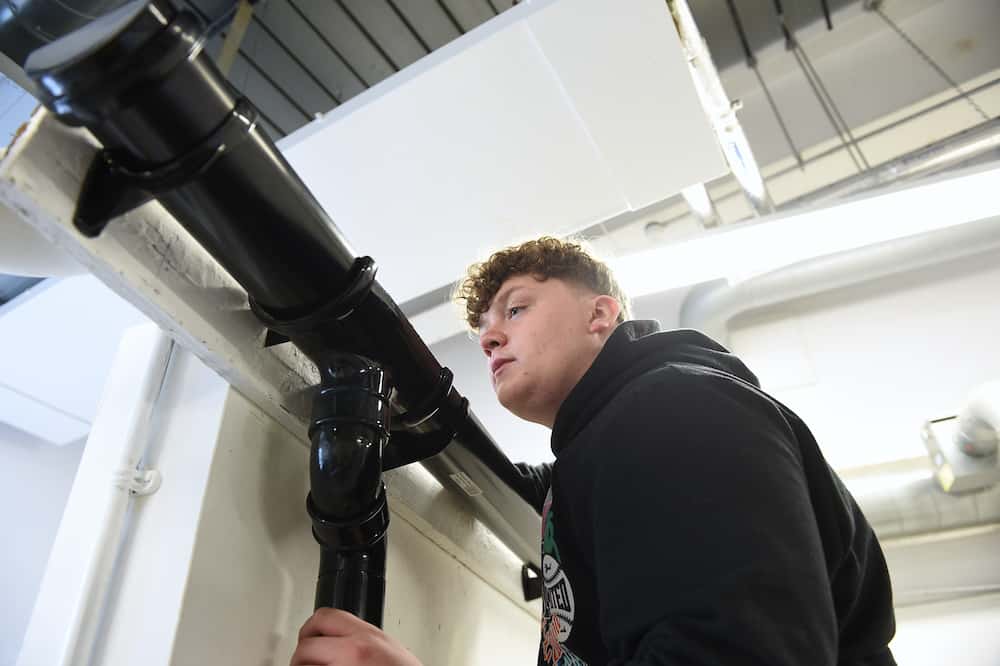 Learner adjusting guttering for water drainage