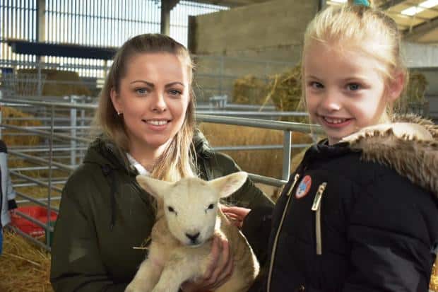 A photo of two people holding a lamb