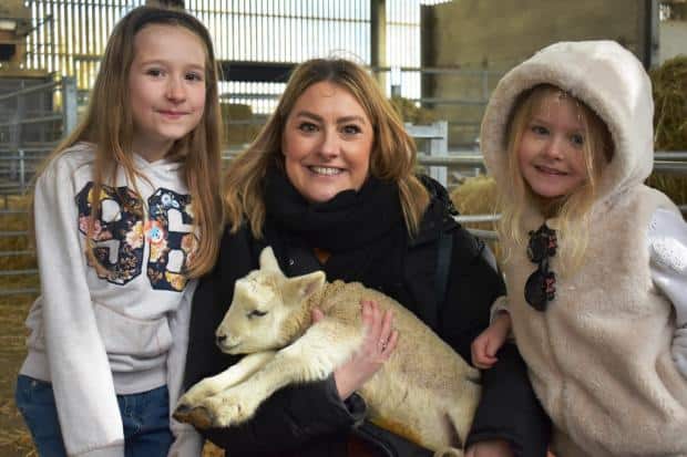 A photo of a parent and children with a lamb