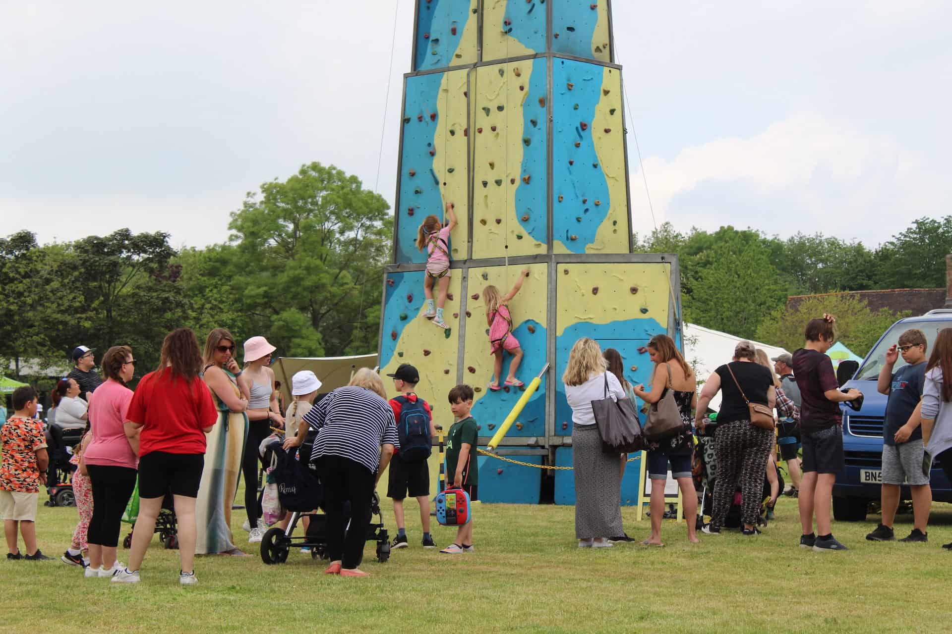 Big Day out event at Suffolk Rural where people are gathered around a climbing wall as two children climb