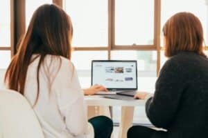 Two adults looking at a laptop screen in a meeting