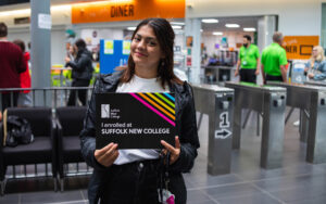 Learner with 'I enrolled at Suffolk New College' sign.