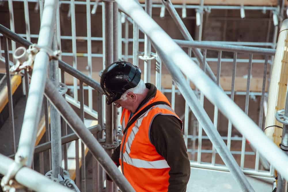 An adult in high viz and hard hat at a construction site.