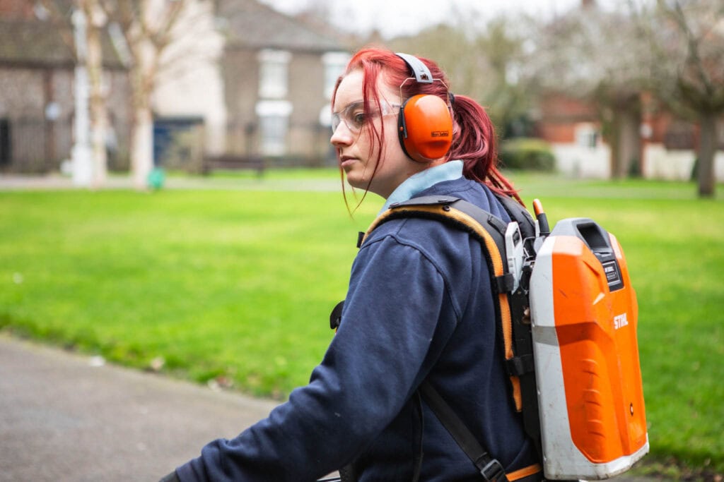 Apprentice trimming hedges