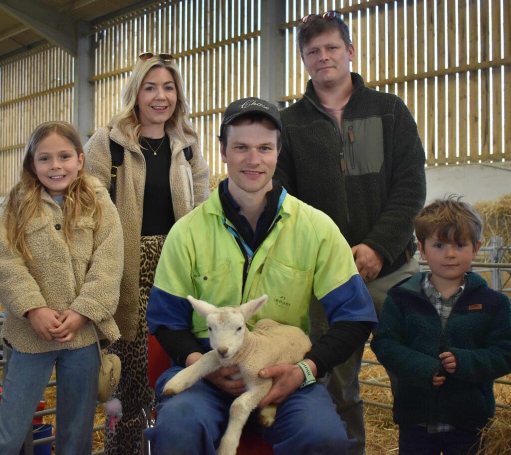 Visitors and farmers with baby lamb