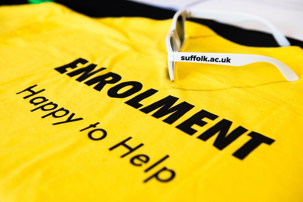 Sunglasses on a tshirt that says Enrolment Happy to Help