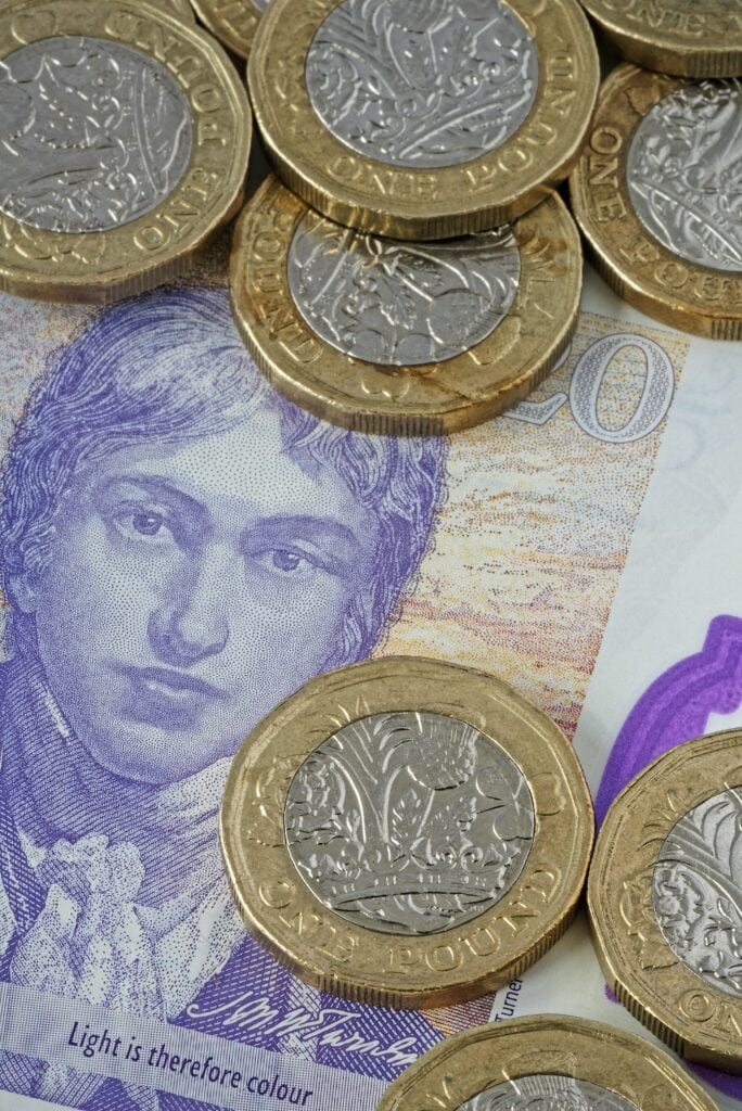 Used £1 (One Pound Sterling) UK Coins in Close Up. On a £ 20 note as background.
