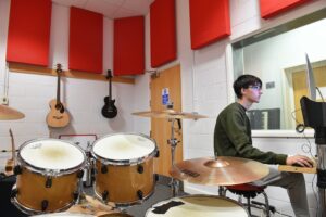 Learner using Rehearsal Suite with iMac and drum kit