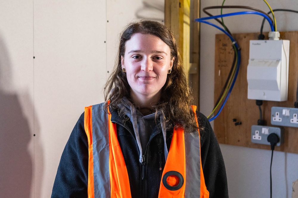 Skilled female apprentice in high-visibility vest working in construction or electrical environment at Suffolk New College for trades training and career development.