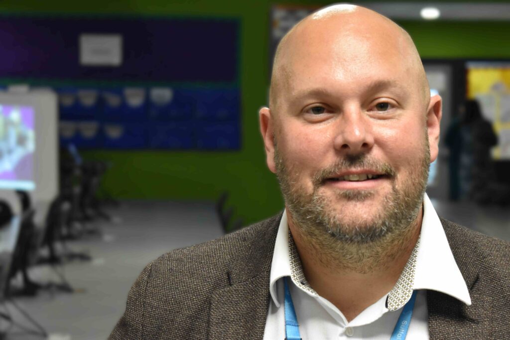 Professional male at Suffolk New College, in a modern classroom environment, showcasing education and student engagement at Suffolk college campus.