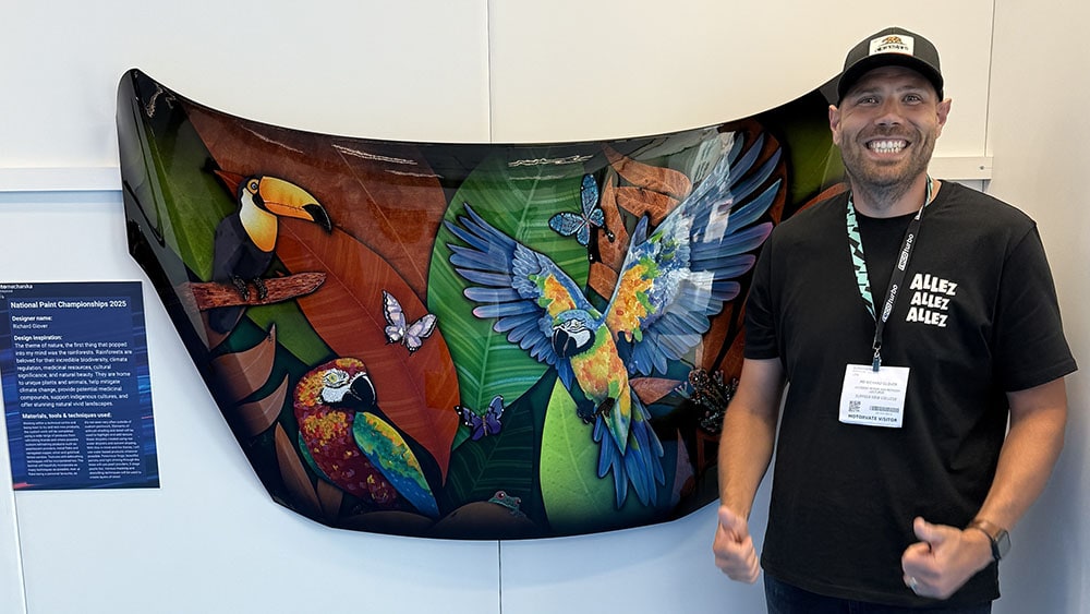 Vibrant tropical bird-themed artwork displayed at Suffolk New College; informative poster on national paint championships 2025 in the foreground.