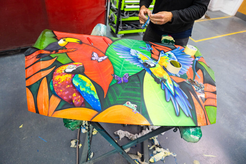 Vibrant colourful parrots and butterflies painted on a table, demonstrating art and creative design skills at Suffolk New College.