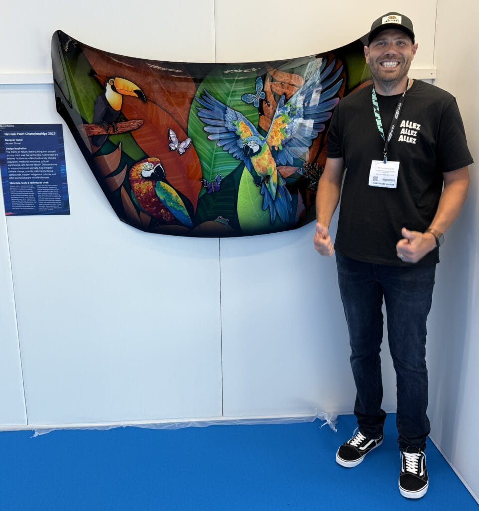 Vibrant rainforest-themed artwork featuring colourful parrots and butterflies displayed at Suffolk New College art exhibition.