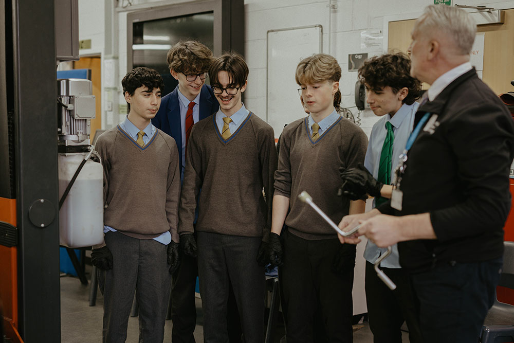 Young male students in school uniforms learning in a technical workshop at Suffolk New College, engaging in practical STEM education.
