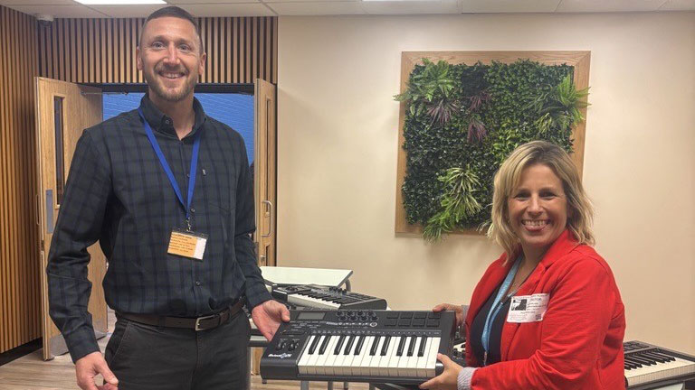 Modern music classroom with staff and equipment.