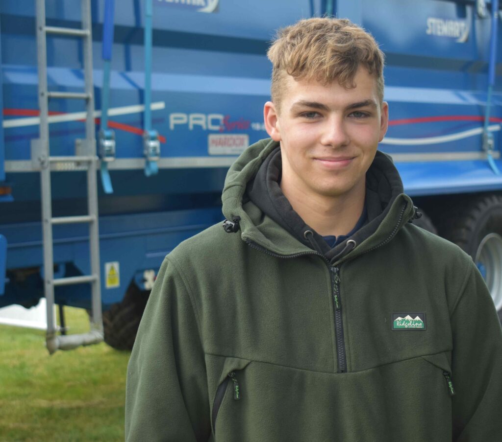 Student posing in front of tractor machinery