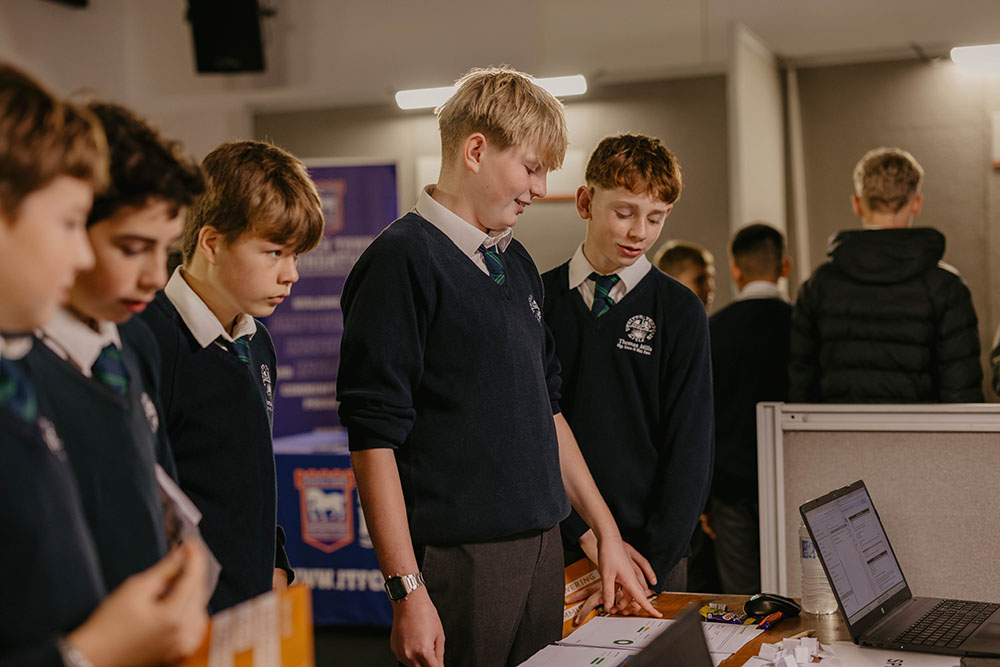 A group of Suffolk New College students discussing project work at an indoor event, showcasing the college’s focus on hands-on learning and modern facilities for student success.