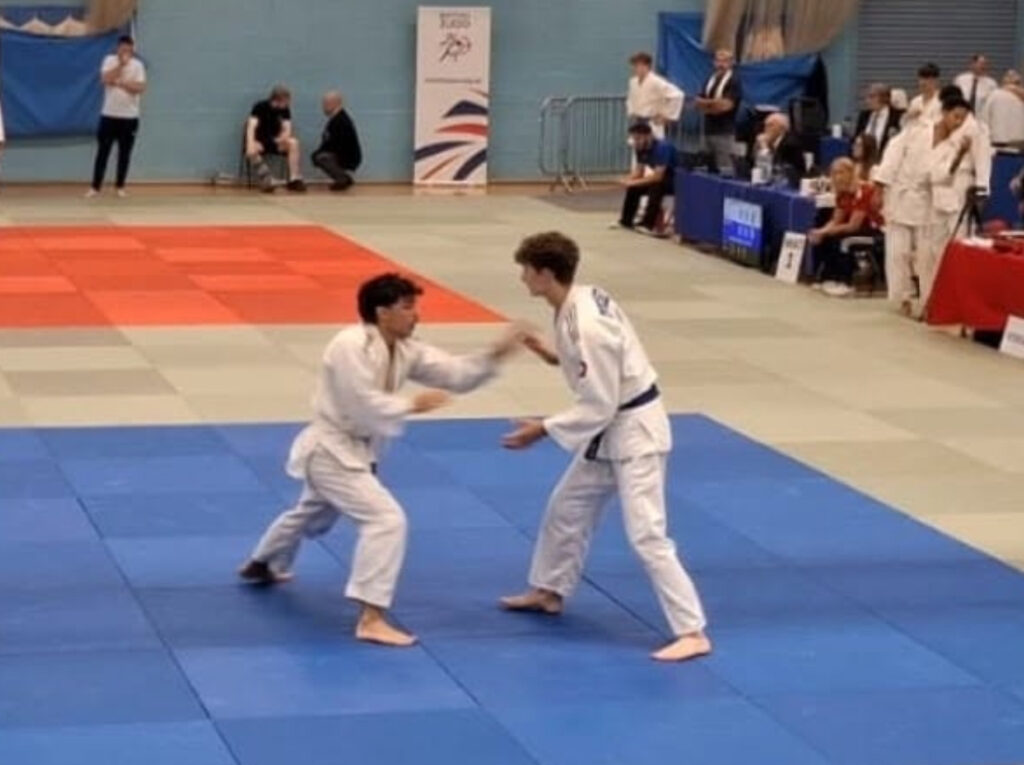 Young competitors practicing martial arts in a sports hall, wearing traditional gi uniforms, during a youth martial arts event at Suffolk New College.