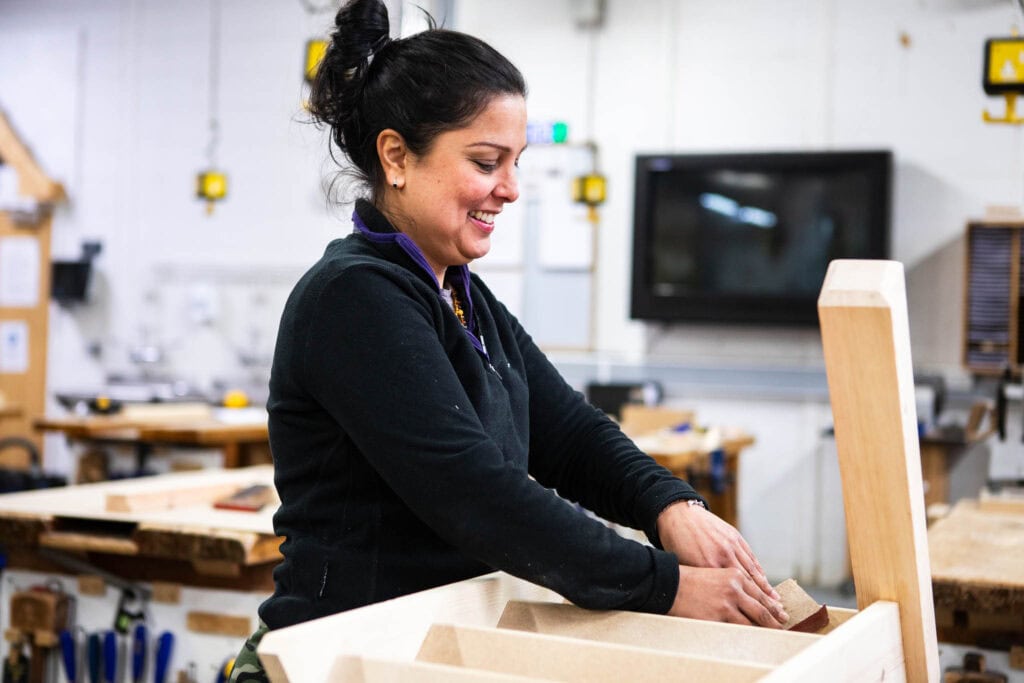 Woman working on a woodworking project in college workshop.