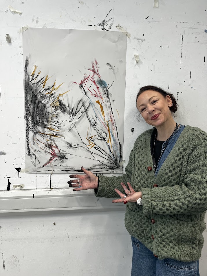 A student proudly showcasing her abstract artwork in Suffolk New College art studio. Focused on contemporary art and creative expression.