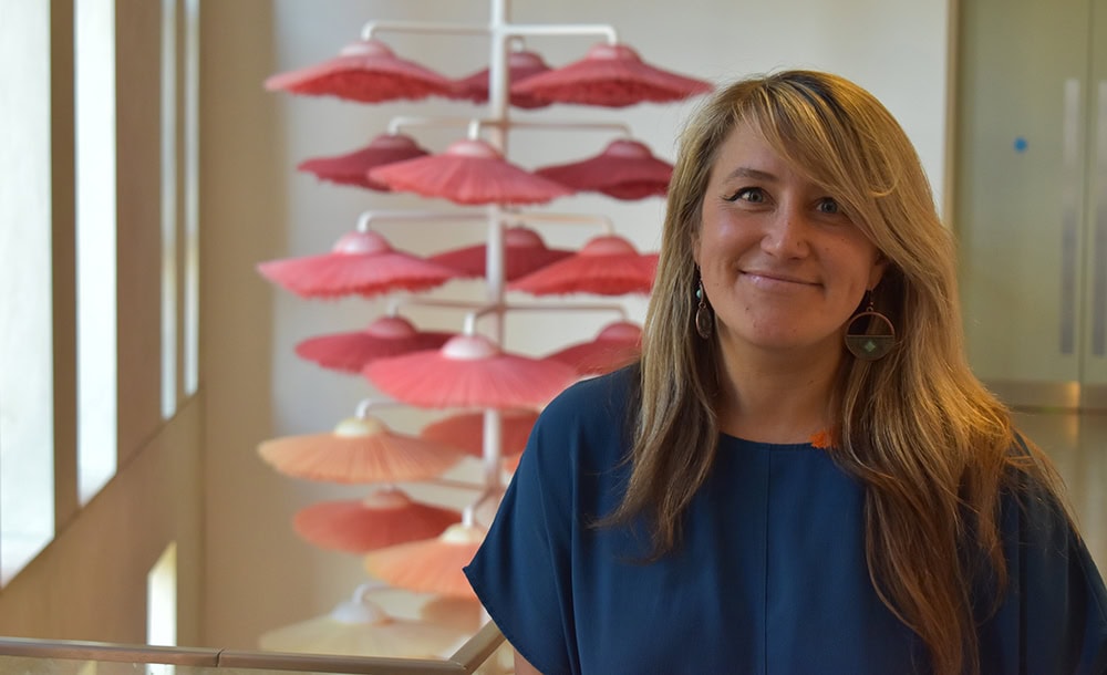 A woman standing inside Suffolk New College, with colourful exhibits in the background, representing diverse educational and creative opportunities at the college.