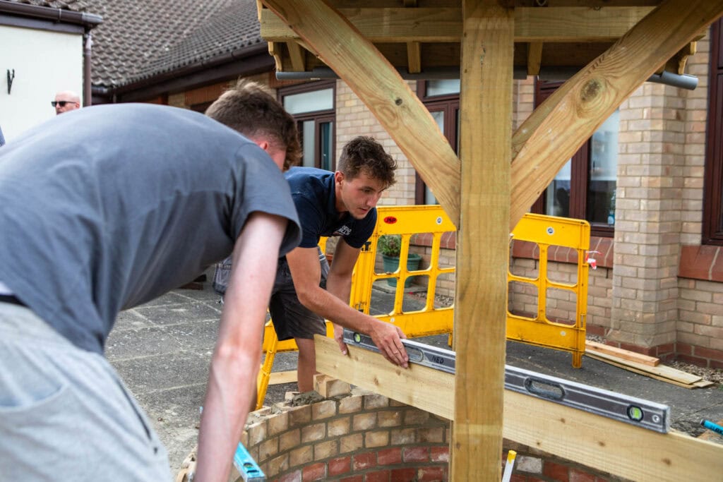 Students practicing bricklaying and carpentry skills outside the college campus.