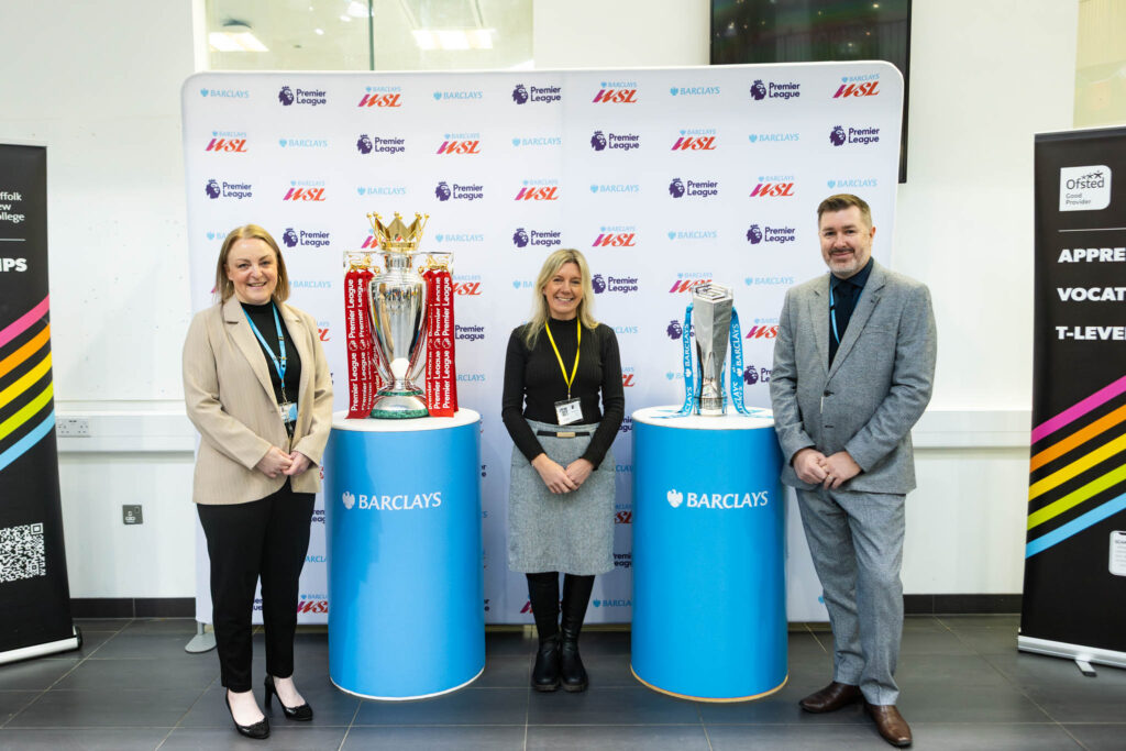 A group of staff from Suffolk New College at an event showcasing football trophies during a student careers festival in Ipswich.