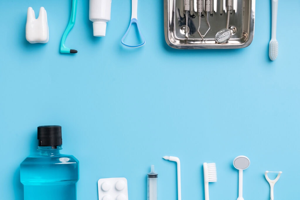 Dental nursing tools and supplies including toothbrushes, dental instruments, and mouthwash arranged on a blue background, highlighting dental training at Suffolk New College.