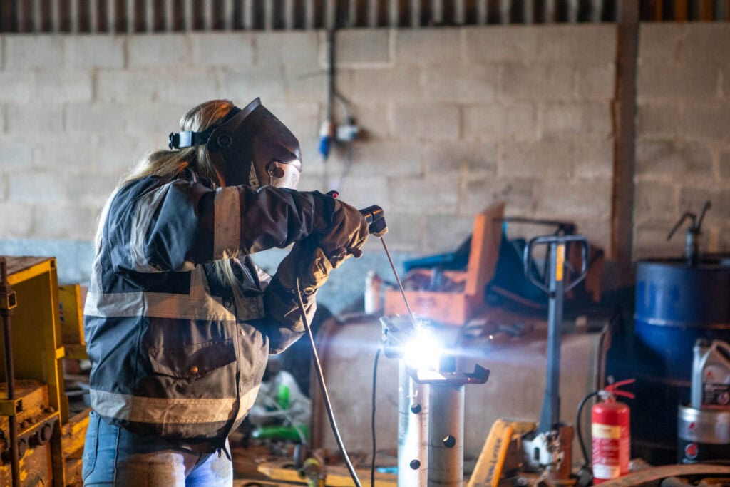 An apprentice welding in a workshop, demonstrating practical skills and hands-on training for career development.