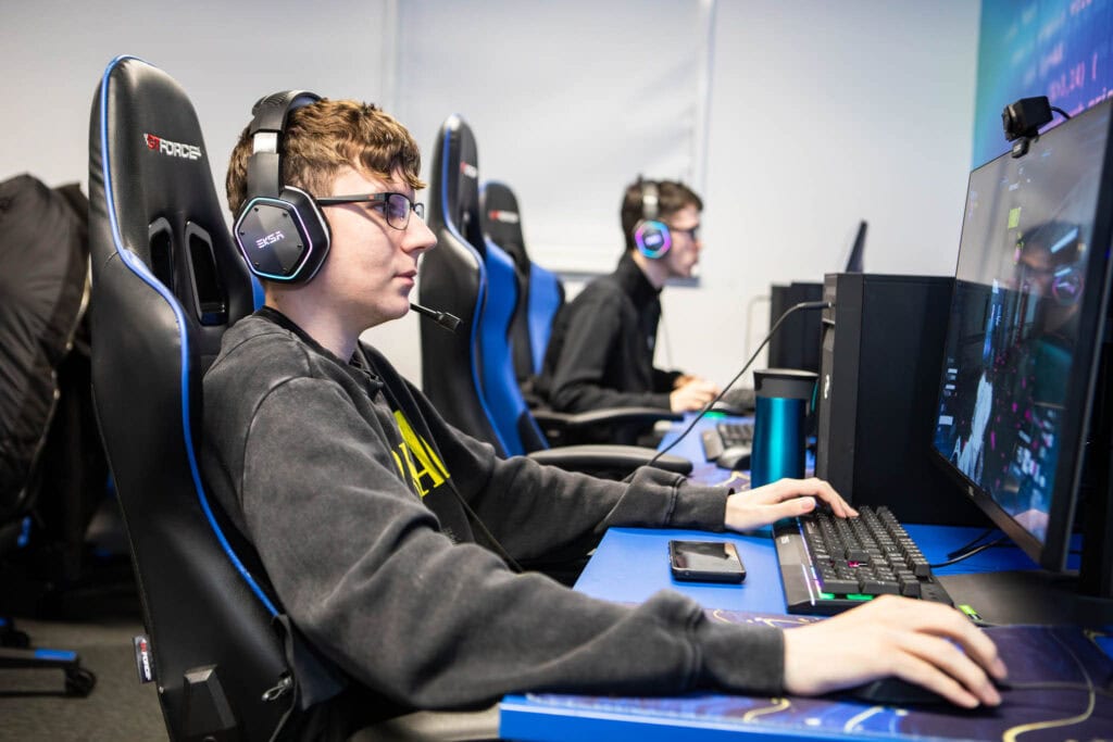 Esports students at Suffolk New College gaming tournament, wearing headsets and playing on high-performance computers during a livestream event for charity.
