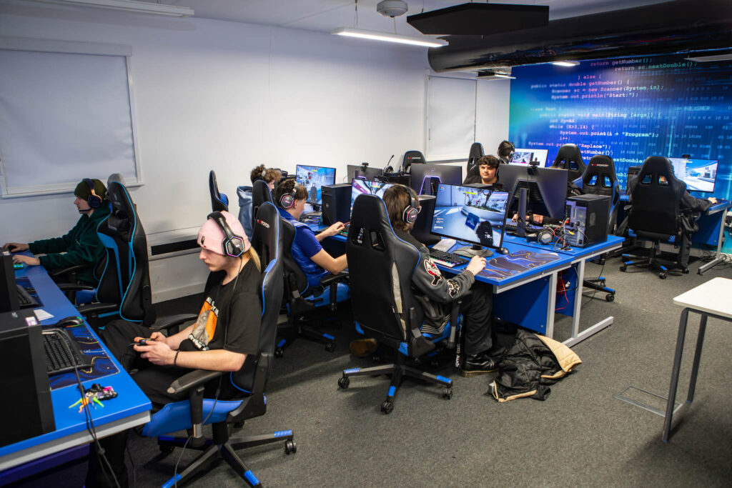 Students at Suffolk New College engaging in esports gaming and livestreaming in a modern computer lab, supporting charity fundraising and developing gaming skills.