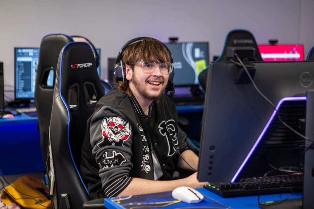 A student at Suffolk New College engaged in computer gaming or eSports training, using high-performance gaming equipment in a modern classroom setting.