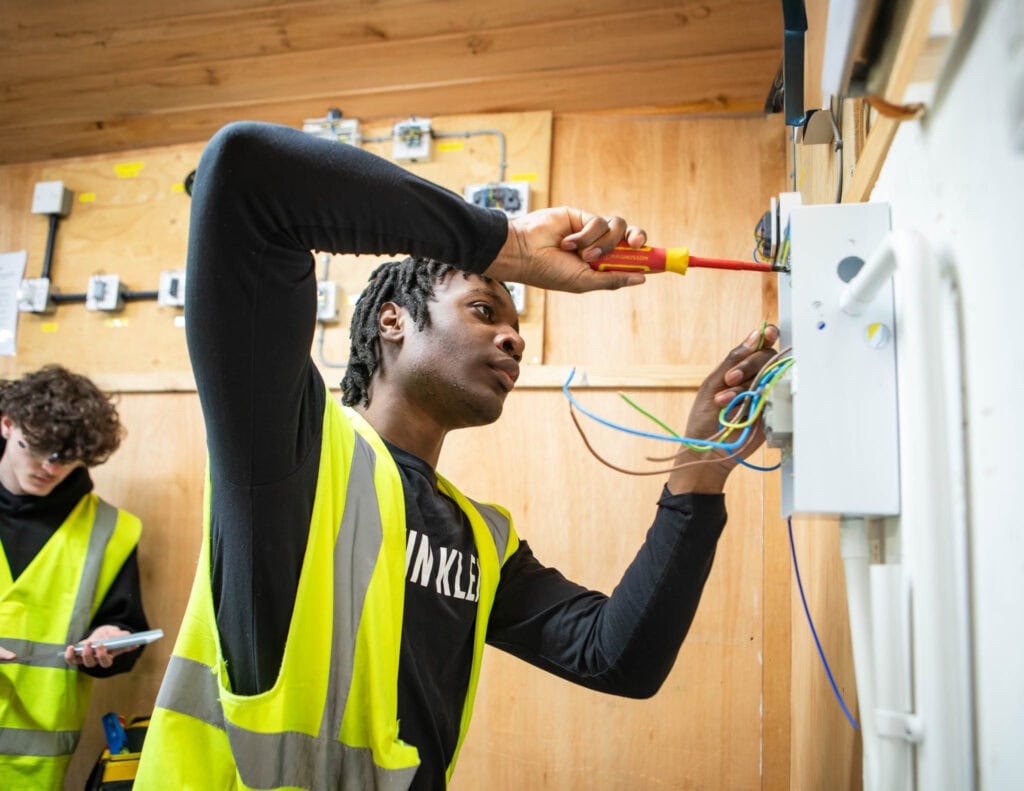 Young adult student working on electrical wiring at Suffolk New College, focusing on technical skills and vocational education in electrical installation.