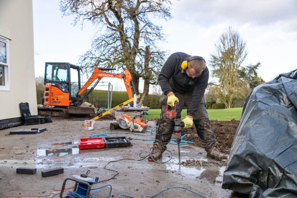 A construction worker using tools to pour concrete on an outdoor site at Suffolk New College, highlighting apprenticeship training in construction trades.