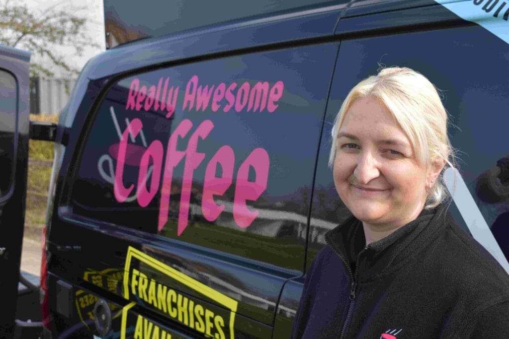 Woman standing next to a Suffolk New College van with "Really Awesome Coffee" branding, promoting a spring family fun day event.