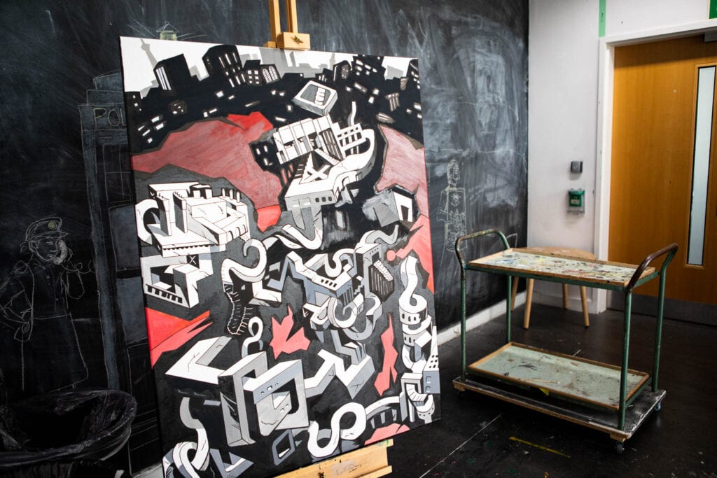 Interior view of an art and design classroom at Suffolk New College, showcasing a large abstract painting with geometric shapes and bold colours, ideal for creative students.