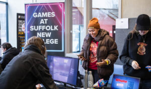 Students engaging in game design activities at Suffolk New College, showcasing modern technology and collaborative learning in a vibrant college environment.